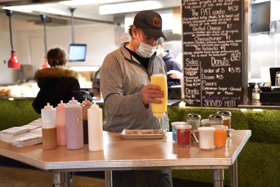 The Test Kitchen’s owner Chris Rahder on Friday, Jan. 28. Rahder is dressing one of their signature donuts with their assortment of custom toppings.